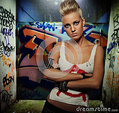 Punk girl with graffiti painted gateway behind her Stock Photo