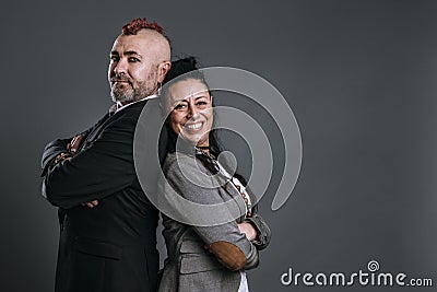 punk-style man and woman dressed in jacket suits pose smiling in studio shot Stock Photo