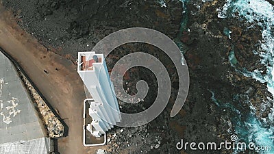 Punta del Hidalgo, Spain - April 22, 2019: AERIAL. Unusual white lighthouse, which stands on the coast of volcanic Editorial Stock Photo