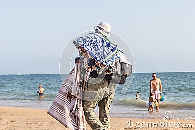 Punta Umbria, Huelva, Spain - August 7, 2020: African immigrant selling their wares on the beach wearing protective or medical Editorial Stock Photo