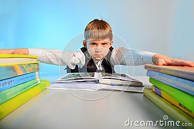 The pupil clings to notebooks and textbooks at his desk, wide-angle photo Stock Photo