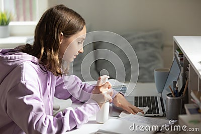 Teenage girl sanitize computer with antibacterial gel at home Stock Photo