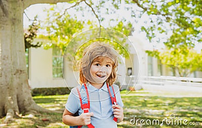 Pupil of primary school with book in hand. Schoolboy with backpack near school outdoors. Beginning of lessons. Stock Photo