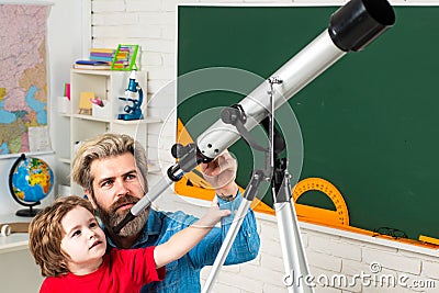 Pupil watching stars with a teacher. Astronomy telescope. Happy cute industrious child is sitting at a desk indoors Stock Photo