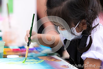 Pupils girl are concentrating on drawing and painting with brush and watercolor on the canvas. Stock Photo