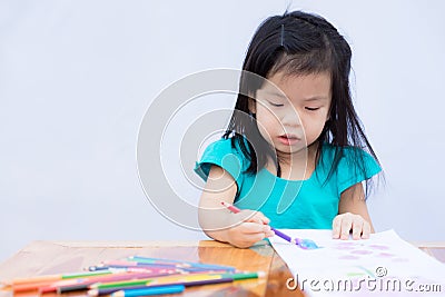 Pupils girl are concentrating on drawing and painting with colored pencils crayon on art paper book. Asian little child learning Stock Photo