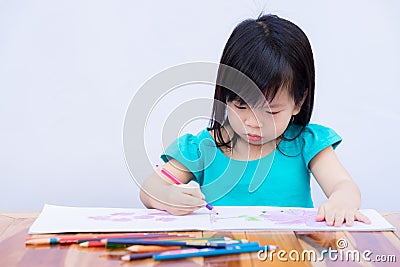Pupils girl are concentrating on drawing and painting with colored pencils crayon on art paper book. Asian little child learning. Stock Photo