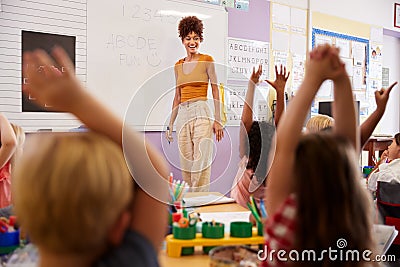 Pupils Raising Hands To Answer Question In Elementary School Maths Lesson Stock Photo