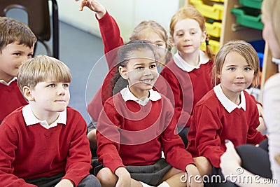 Pupils Sitting On Mat Listening To Teacher Stock Photo