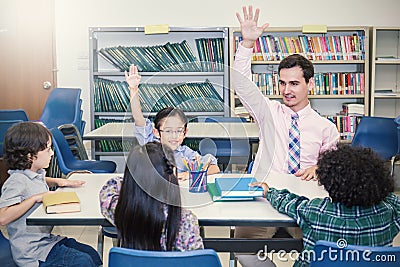 Pupils Studying with teacher At Desks In Classroom, Stock Photo