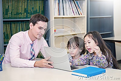 Pupils studying with teacher using computer device in classroom Stock Photo