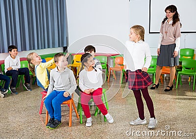 Pupils with teacher playing musical chairs Stock Photo