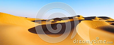panoramic view featuring pure golden sand dunes under a serene blue sky with copy space Stock Photo