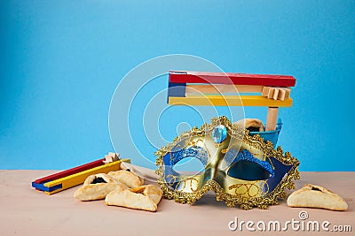 Purim celebration concept with hamantashen cookies, Purim mask and toy noisemaker on blue background Stock Photo