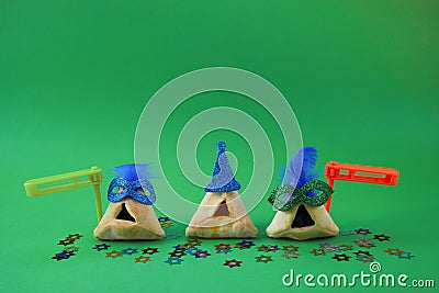 Purim celebration concept. Traditional Hamantashen cookies with clown hat and gragger. Stock Photo