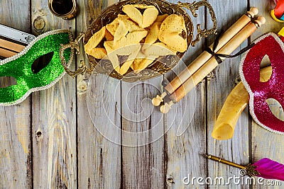 Purim traditional with hamantaschen cookies, noisemaker and carnival mask on wood background Stock Photo