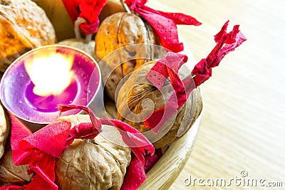 Purple candle with decorated wallnuts in a wooden bowl Stock Photo