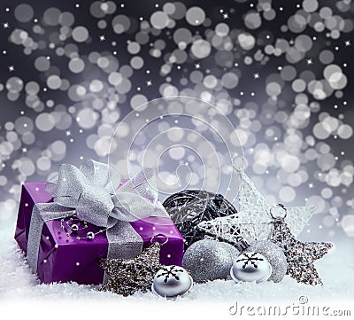Purple Christmas package , gift of a silver ribbon. Jingle bells , silver christmas balls and christmas stars put on snow. Stock Photo