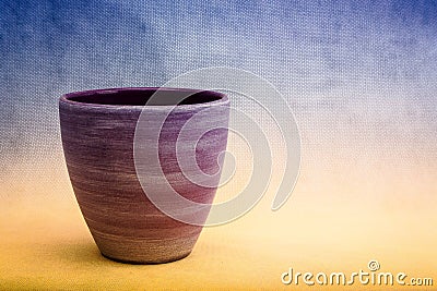 A purple clay plant-pot against a blue and yellow background Stock Photo