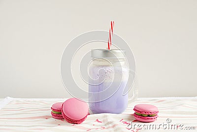 Purple coffee in stylized mason jar cup with macarons and colorful decoration. Blueberry milk shake, cocktaill, frappuccino. Unico Stock Photo