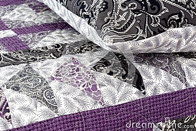 Purple coloured handmade patchwork bed quilt and pillow with various fabric geometric patterns Stock Photo