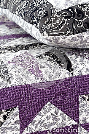 Purple coloured handmade patchwork bed quilt and pillow with various fabric geometric patterns Stock Photo