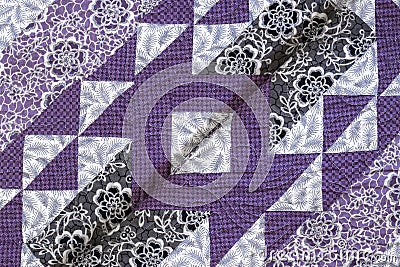 Purple coloured handmade patchwork bed quilt with various fabric geometric patterns Stock Photo