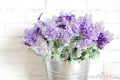 Purple fabric lavender flowers in bucket on white brick wall Stock Photo