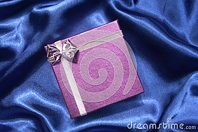Purple gift box on blue silk Stock Photo