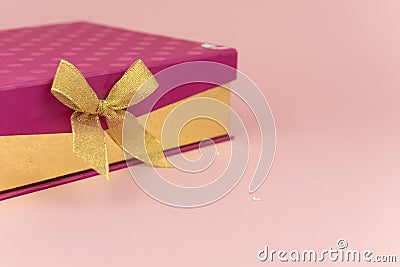 Purple gift box with gold ribbon bow on pink background. milimalism. Sales, shopping, christmas winter and birthday Stock Photo