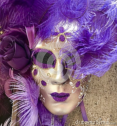 Purple and gold venetian masquerade mask hanging on a wall Stock Photo