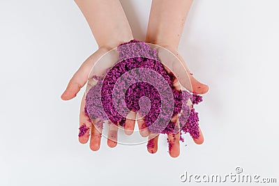 Purple kinetic sand. Child sculpts and plays with sand. Close-up view. White background Stock Photo