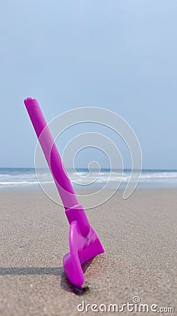 Purple little shovel toy at beach white sand blue sky little wave Stock Photo