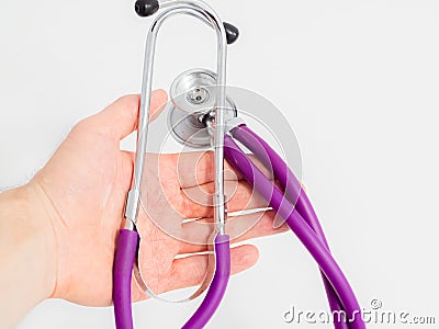 Purple stethoscope in doctor`s hand on white background. Close-up. Stock Photo