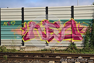Purple,yellow and pink graffiti on a noise barrier wall Editorial Stock Photo
