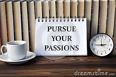 PURSUE YOUR PASSIONS - words on white notebook on background of books, clock and cup of coffee Stock Photo