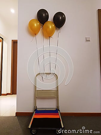 Push trolley decorated with gold and black helium balloons to tr Stock Photo