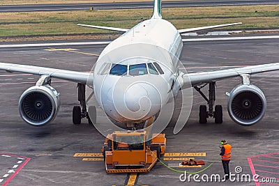 Pushback tractor is towing the aircraft to a parking lot, aviation marshall. Close up view Editorial Stock Photo