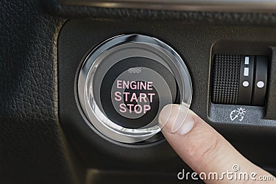 Pushing the engine start stop button of a car Stock Photo