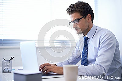 Put in the work and success will follow. a handsome young businessman working on a laptop. Stock Photo