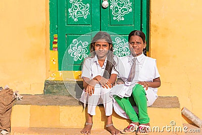 PUTTAPARTHI, ANDHRA PRADESH, INDIA - JULY 9, 2017: Two cute Indian girl sitting on the doorstep. Copy space for text. Editorial Stock Photo