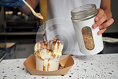 Putting crunchy topping on a brownie and vanilla icecream Stock Photo