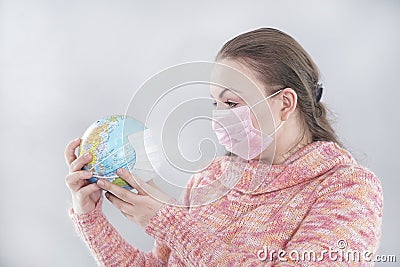 Putting a green surgical face mask on the globe sphere model. Heal the world from coronavirus covid-19 concept Stock Photo