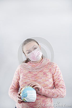 Putting a green surgical face mask on the globe sphere model. Heal the world from coronavirus covid-19 concept Stock Photo