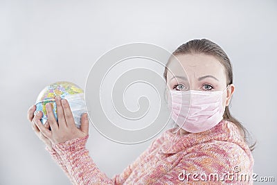 Putting a green surgical face mask on the globe sphere model. Heal the world from coronavirus covid-19 concept Stock Photo