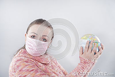 Putting a green surgical face mask on the globe sphere model. Heal the world from coronavirus covid-19 concept Stock Photo