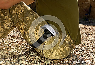 Putting a tourniquet on the leg of a wounded soldier. Stock Photo