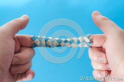 Puzzle game and logic games concept with hands playing with a chinese finger trap, a toy that the more you pull the tighter it Stock Photo