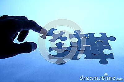 Puzzle with a loose piece touched by a hand Stock Photo