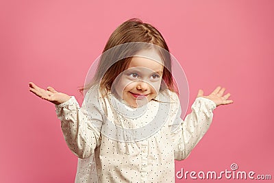 Puzzled child shrugs her shoulders and raises hands, expresses ignorance or difficulty, does not know answer to the Stock Photo